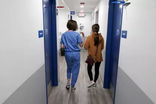 Dr. Elizabeth Brett Daily, left, walks with patient Haley Ruark after providing a medical abortion at a Planned Parenthood clinic Wednesday, Oct. 12, 2022, in Kansas City, Kan. (AP Photo/Charlie Riedel)