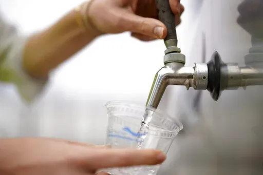 An official at the Carlsbad Desalination plant fills a cup with filtered water made from ocean water, Thursday, May 26, 2022, in Carlsbad, Calif.The facility is the Western hemisphere's largest desalination plant, which removes salt and impurities from ocean water. (AP Photo/Gregory Bull)