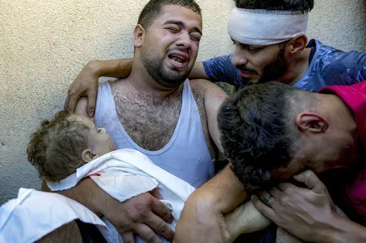 Palestinian Mahmoud Mikdad morns as holding the body of his 21-month-old child Yaman, killed in the Israeli bombardment of the Gaza Strip, at a hospital morgue in Deir al-Balah, Tuesday, July 16, 2024. (AP Photo/Abdel Kareem Hana)