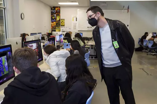 In this photo provided by the Hays Consolidated Independent School District, Brian McKinney, right, who has children in the Hays Consolidated Independent School District, in Kyle, Texas, teaches a class at Johnson High School, in Buda, Texas, Thursday, Jan. 27, 2022. McKinney, a small business owner and former teacher, is among parents the district has hired to work as substitute teachers during a staffing crunch. He returned to the classroom after about 15 years away. (Moses Leos III/Hays Conso