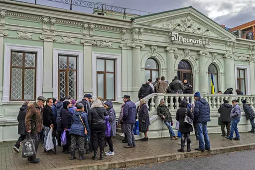 Residents queue at a bank branch in Kherson, southern Ukraine, Nov. 21, 2022. Even as Ukraine celebrates recent battlefield victories, its government faces a looming challenge on the financial front: how to pay the enormous cost of the war effort without triggering out-of-control price spikes for ordinary people or piling up debt that could hamper postwar reconstruction. (AP Photo/Bernat Armangue, File)