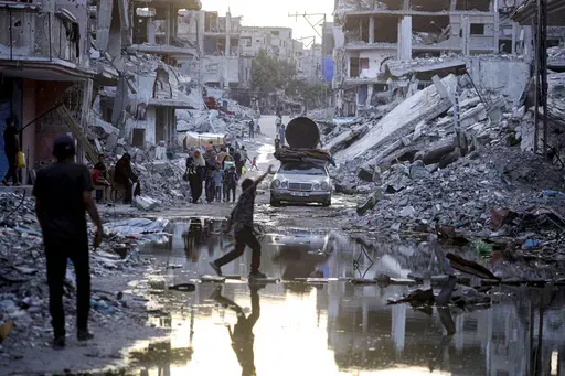Palestinians displaced by the Israeli air and ground offensive on the Gaza Strip, walk past sewage flowing into the streets of the southern town of Khan Younis, Gaza Strip, on July 4, 2024. Israel’s military on Sunday Aug. 25, 2024 said polio vaccines for more than 1 million people had been delivered to Gaza, after the first confirmed case of the disease in the territory in a quarter-century. (AP Photo/Jehad Alshrafi, File)