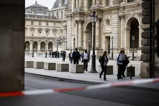 Staff leave the Louvre Museum as people are evacuated after it received a written threat, in Paris, Saturday Oct. 14, 2023. The Louvre Museum says it is closing for the day and evacuating all visitors and staff after a threat. (AP Photo/Thomas Padilla)