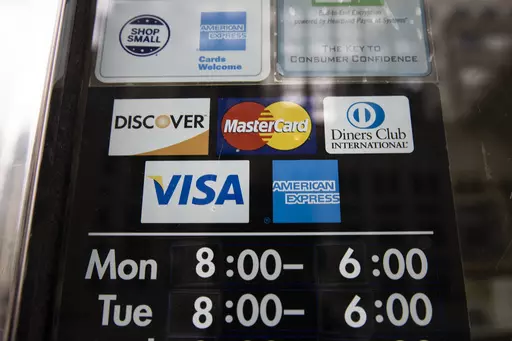 Credit card options are shown on a store's door on Nov. 29, 2018 in Philadelphia. Noticeable pockets of Americans are quickly running up their credit card balances and increasing numbers are now falling behind on their debts. (AP Photo/Matt Rourke, File)