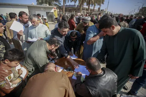 Supporters of the Shiite cleric Muqtada al-Sadr sign a pledge to stand against homosexuality or LGBTQ, outside a mosque in Kufa, Iraq, Friday, Dec. 2, 2022. Human rights groups and diplomats criticized a law that was quietly passed by the Iraqi parliament over the weekend that would impose heavy prison sentences on gay and transgender people. (AP Photo/Anmar Khalil, File)