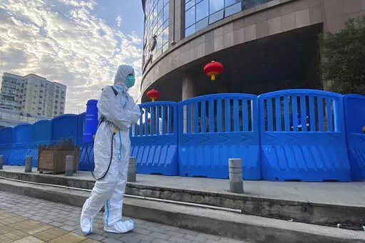 A worker in protectively overalls and carrying disinfecting equipment walks outside the Wuhan Central Hospital, China on  Feb. 6, 2021. Experts drafted by the World Health Organization to help investigate the origins of the coronavirus pandemic say further research is needed to determine how COVID-19 first began. They say they need a more detailed analysis of the possibility it was a laboratory accident. (AP Photo/Ng Han Guan, File)