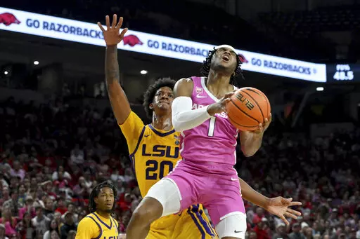 Arkansas guard Ricky Council IV (1) drives past LSU forward Derek Fountain (20) to score during the second half of an NCAA college basketball game Tuesday, Jan. 24, 2023, in Fayetteville, Ark. (AP Photo/Michael Woods)