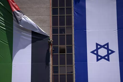 A Palestinian flag is removed from a building by Israeli authorities after being put up by an advocacy group that promotes coexistence between Palestinians and Israelis, in Ramat Gan, Israel, Wednesday, June 1, 2022. In recent weeks, Israeli authorities have gone out of their way to challenge the hoisting of the Palestinian flag. Palestinian citizens of Israel see the campaign against the flag as another affront to their national identity and their rights as a minority in the majority Jewish sta