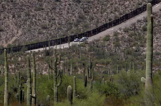 U.S. Customs and Patrol Patrol agents sit along a section of the international border wall that runs through Organ Pipe Cactus National Monument, Thursday, Aug. 22, 2019 in Lukeville, Ariz. U.S. Border Patrol agents answering reports of gunfire shot and killed a man on a tribal reservation in southern Arizona after he abruptly threw something and raised his arm, the agency said Monday, May 22, 2023. (AP Photo/Matt York, File)