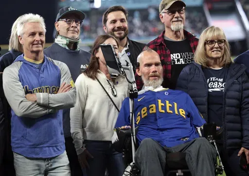 Former NFL football player and ALS patient Steve Gleason, second from right, and Pearl Jam guitarist Mike McCready, left, participate in ceremonies in commemoration of Lou Gehrig Day before a baseball game between the Seattle Mariners and the Los Angeles Angels, Sunday, June 2, 2024, in Seattle. Retired NFL safety Steve Gleason, who has been fighting ALS since 2011, will receive the Arthur Ashe Award for Courage at The ESPYS on July 11. (AP Photo/Jason Redmond, File)
