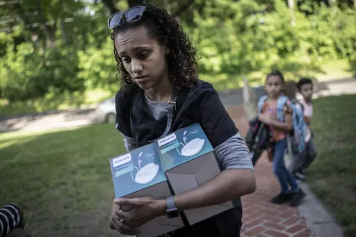 Catherine Manson unloads home nebulizer units from her car while her children, Caydence Manson, center, and Carter Manson, follow behind after they were picked up from school in Hartford, Conn., on Wednesday, May 25, 2022. All three of them suffer from asthma. The children have missed weeks of school, leaving them behind in schoolwork at a critical juncture for their education. And in turn, their parents were forced to miss work to care for them – putting a strain on the family’s finances. (