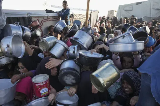 Palestinian women and girls struggle to reach for food at a distribution center in Khan Younis, Gaza Strip Friday, Dec. 6, 2024. (AP Photo/Abdel Kareem Hana, File)