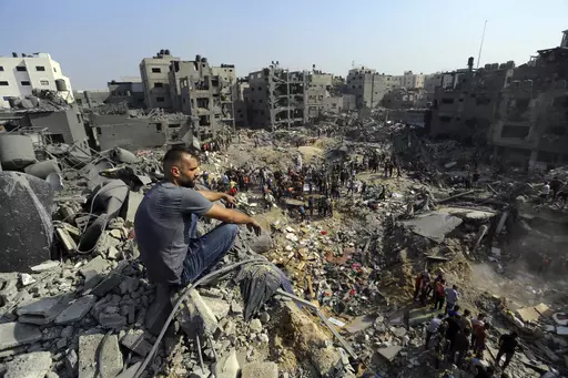 A man sits on the rubble as others wander among debris of buildings that were targeted by Israeli airstrikes in Jabaliya refugee camp, northern Gaza Strip on Nov. 1, 2023. Weeks after ordering northern Gaza's 1.1 million inhabitants to evacuate south, the Israeli army is intensifying its bombing of the area that stretches to the wetlands of Wadi Gaza. Israeli soldiers are also battling Hamas militants just north of Gaza City. It's the start of what officials expect to be a long and bloody invasi