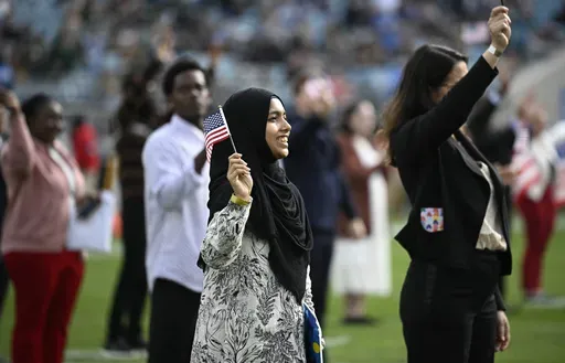 New United States citizens wave American flags during a naturalization ceremony during halftime at an NFL football game between the Jacksonville Jaguars and the New York Jets, Dec. 15, 2024, in Jacksonville, Fla. (AP Photo/Phelan M. Ebenhack, File)