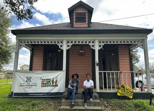 Twin sisters Jo and Joy Banner pose on the porch of their place of business, Fee-Fo-Lay Café, March 13, 2024, Wallace, La. (AP Photo/Stephen Smith)