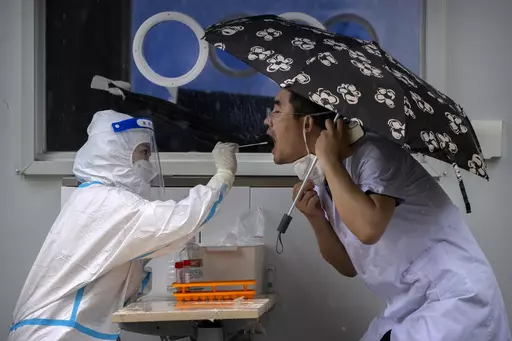 A worker wearing a protective suit swabs a man's throat for a COVID-19 test at a coronavirus testing site in Beijing, on June 22, 2022. The World Health Organization said Friday May 5, 2023 that COVID-19 no longer qualifies as a global emergency, marking a symbolic end to the devastating coronavirus pandemic that triggered once-unthinkable lockdowns, upended economies and killed millions of people worldwide. (AP Photo/Mark Schiefelbein, File)
