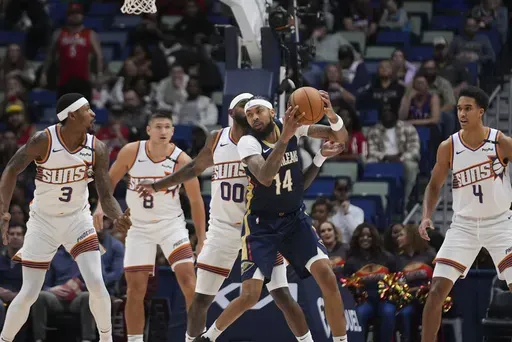 New Orleans Pelicans forward Brandon Ingram (14) looks to pass around Phoenix Suns guard Bradley Beal (3), guard Grayson Allen (8), forward Royce O'Neale (00) and center Oso Ighodaro (4) in the first half of an NBA basketball game in New Orleans, Thursday, Dec. 5, 2024. (AP Photo/Gerald Herbert)