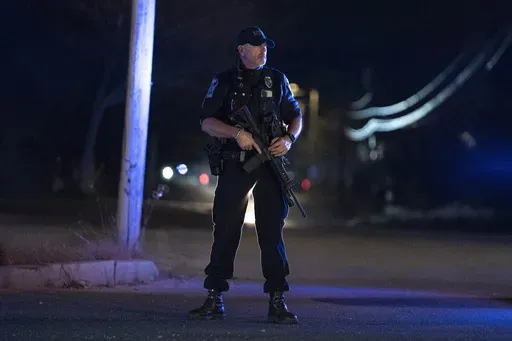 A police officer guards the road where the body of suspected mass shooter Robert Card was found, Friday, Oct. 27, 2023, in Lisbon, Maine. Despite warnings of deteriorating mental health, drunken threats and guns, the sheriff department chose to avoid confronting the Army reservist who later killed 18 people and work with family and the Army to get him help, states the report, released late Thursday, Dec. 14, 2023. (AP Photo/Robert F. Bukaty, File)