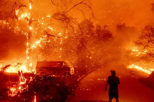 Bruce McDougal watches embers fly over his property as the Bond Fire burns through the Silverado community in Orange County, Calif., on Dec. 3, 2020. The United Nations on Monday, Feb. 28, 2022, released a new report on climate change. (AP Photo/Noah Berger, File)