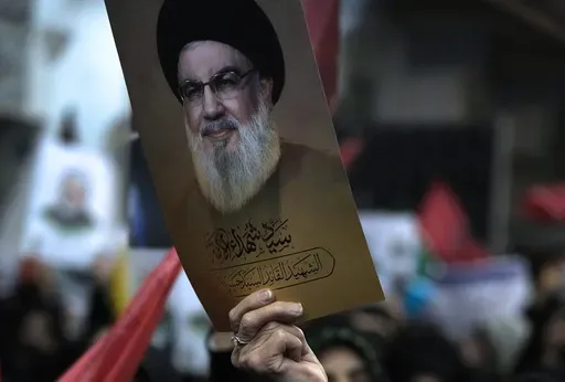 A woman holds up a poster of the slain Hezbollah leader Hassan Nasrallah during a ceremony marking death anniversary of the late commander of the Iran's Revolutionary Guard expeditionary Quds Force, Gen. Qassem Soleimani, who was killed in a U.S. drone attack in 2020, at the Imam Khomeini grand mosque in Tehran, Iran, Thursday, Jan. 2, 2025. (AP Photo/Vahid Salemi)