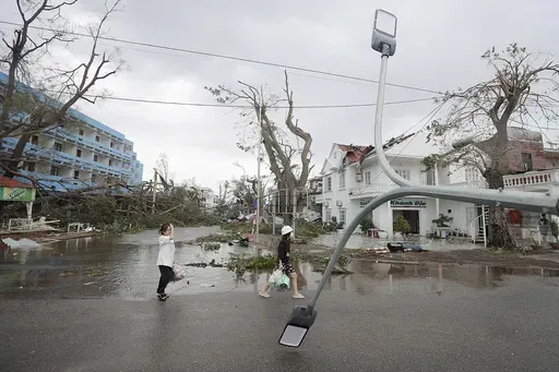 People walk past broken light post after typhoon Yagi hit the city, in Hai Phong, northern Vietnam on Sunday, Sept. 8, 2024. (Minh Quyet/VNA via AP)