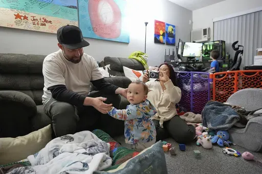 Steve Petersen, left, and his wife Jennifer watch as their daughter Carolynn tries to stand inside their apartment in Campbell, Calif., Wednesday, Jan. 15, 2025. (AP Photo/Godofredo A. Vásquez)