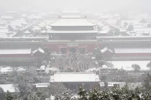 The snow covered Forbidden City is seen from a hilltop pavilion in Beijing, Wednesday, Dec. 13, 2023. Throngs of people in boots and down parkas climbed a hill that overlooks the Forbidden City this week to jostle with others trying to get a shot of the snow-covered roofs of the former imperial palace. (AP Photo/Ng Han Guan)