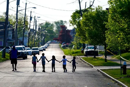 Children walk hand in hand in a street near the scene of a shooting at a supermarket in Buffalo, N.Y., Sunday, May 15, 2022. Long before an 18-year-old avowed white supremacist inflicted terror at a Buffalo supermarket, the city's Black neighborhoods, like many others around the nation, had been dealing with wounds that are generations old. (AP Photo/Matt Rourke, File)