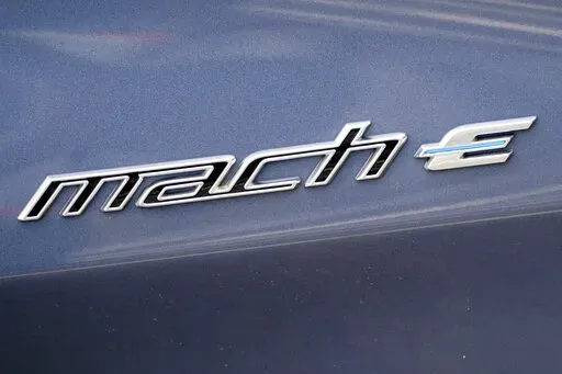 In this photo made on Thursday, May 6, 2021, the badging logo is seen on a 2021 Ford Mustang Mach E at a Ford dealer in Wexford, Pa. Ford is spinning off its electric vehicles and internal combustion businesses into separate units. The automaker said Wednesday, March 2, 2022 that its plan includes two distinct, but strategically interdependent, auto businesses – Ford Blue and Ford Model e.  (AP Photo/Keith Srakocic)