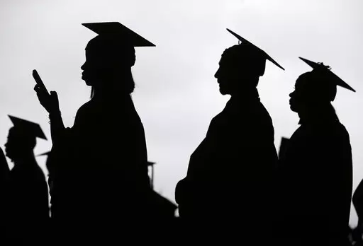 In this May 17, 2018, file photo, new graduates line up before the start of the Bergen Community College commencement at MetLife Stadium in East Rutherford, N.J.  A deadline is fast approaching for teachers, librarians, nurses and others who work in public service to apply to have their student loan debt forgiven. New figures from the U.S. Department of Education show 145,000 borrowers have had the remainder of their debt canceled through the Public Service Loan Forgiveness program. (AP Photo/Se