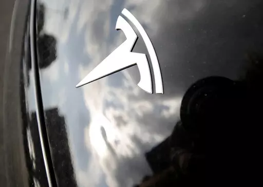 In this July 8, 2018, file photo, clouds are reflected above the company logo on the hood of a Tesla vehicle outside a showroom in Littleton, Colo. California prosecutors have filed two counts of vehicular manslaughter against the driver of a Tesla on Autopilot that ran a red light, slammed into another car and killed two people in 2019. The defendant appears to be the first person to be criminally charged in the United States for a fatal crash involving a motorist who was using a partially auto