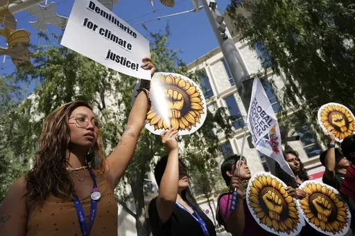 Mitzi Jonelle Tan, of the Philippines, holds a sign reading "demilitarize for climate justice" at a demonstration at the COP28 U.N. Climate Summit, Monday, Dec. 4, 2023, in Dubai, United Arab Emirates. (AP Photo/Peter Dejong)