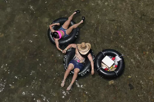 Tubers float the cool Comal River in New Braunfels, Texas, Thursday, June 29, 2023. Meteorologists say scorching temperatures brought on by a heat dome have taxed the Texas power grid and threaten to bring record highs to the state. (AP Photo/Eric Gay)