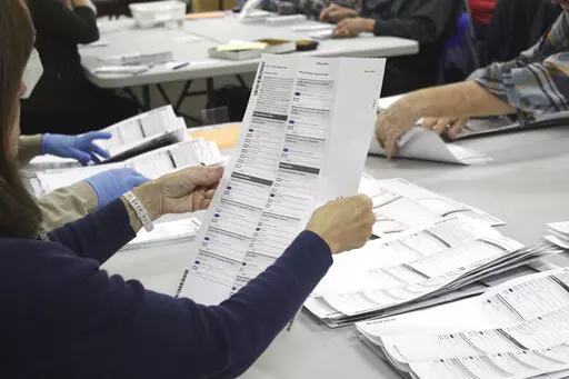 An election worker examines a ballot at the Clackamas County Elections office on Thursday, May 19, 2022, Oregon City, Ore. Since the 2020 election, election officials and workers have faced an onslaught of harassment and threats stemming from false claims it was stolen from former President Donald Trump. (AP Photo/Gillian Flaccus, File)