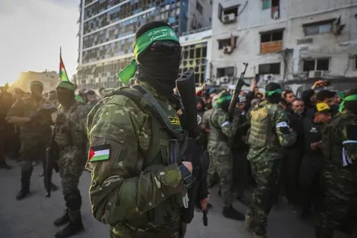 Fighters from the Qassam Brigades, the military wing of Hamas, control the crowd as Red Cross vehicles manoeuvre to collect Israeli hostages to be released under a ceasefire agreement between Israel and Hamas, in Gaza City, Sunday, Jan. 19, 2025. (AP Photo/Abed Hajjar)