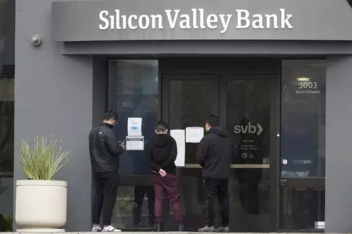 People look at signs posted outside of an entrance to Silicon Valley Bank in Santa Clara, Calif., Friday, March 10, 2023. From winemakers in California to startups across the Atlantic Ocean, companies are scrambling to figure out how to manage their finances after their bank, Silicon Valley Bank, suddenly shut down on Friday. The meltdown means distress not only for businesses but also for all their workers whose paychecks may get tied up in the chaos. (AP Photo/Jeff Chiu)