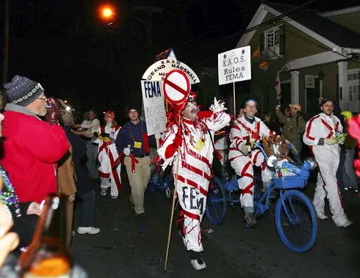 The satirical Krewe du Vieux parade makes its way through the French Quarter as it laughs at authorities and tragedy of Hurricance Katrina and aftermath, Saturday, Feb. 11, 2006, in New Orleans. New Orleans’ health director says she won’t take part in one of the earliest of the Mardi Gras season parades in 2022, citing threats after the resumption of COVID-19 restrictions in the city. (AP Photo/Mary Ann Chastain, File)