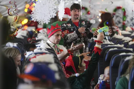Flight attendant Gustavo Oliveira, center, juggles bubbles to entertain passengers during the United Airlines annual "fantasy flight" to a fictional North Pole at Denver International Airport, Saturday, Dec. 14, 2024, in Denver. (AP Photo/David Zalubowski)