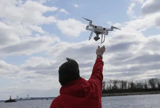 In this April 29, 2018, file photo, a drone operator helps to retrieve a drone after photographing over Hart Island in New York. (AP Photo/Seth Wenig, File)