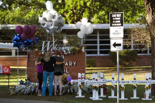 A family pays their respects next to crosses bearing the names of Tuesday's shooting victims at Robb Elementary School in Uvalde, Texas, Thursday, May 26, 2022. (AP Photo/Jae C. Hong, File)