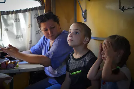 People evacuated from the war hit area sit inside an evacuation train waiting for departure in Pokrovsk, eastern Ukraine, Saturday, June 11, 2022. (AP Photo/Efrem Lukatsky)