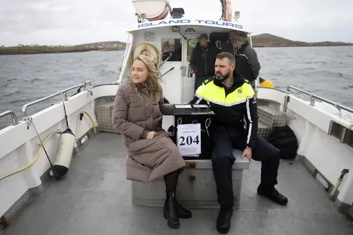 Presiding officer Caroline Sharkey and Garda Ronan Steede look after a ballot box that is taken by boat to the Island of Gola as voters go to polls the for the 2024 General Election in Ireland, Friday, Nov. 29, 2024. (AP Photo/Peter Morrison)