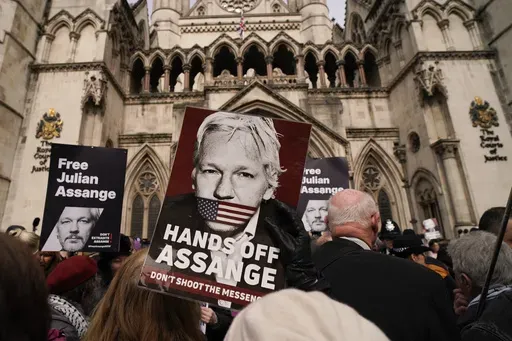 Demonstrators hold placards after Stella Assange, wife of Wikileaks founder Julian Assange, released a statement outside the Royal Courts of Justice, in London, Tuesday, March 26, 2024. Two High Court judges said they would grant Assange a new appeal unless U.S. authorities give further assurances about what will happen to him. The case has been adjourned until May 20. (AP Photo/Alberto Pezzali)