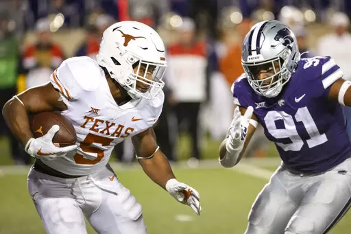 Texas running back Bijan Robinson (5) is pursued by Kansas State defensive end Felix Anudike-Uzomah (91) during the second half of an NCAA college football game on Nov. 5, 2022, in Manhattan, Kan. In an age of “opt-outs” in college football, the best NFL prospects for Alabama and Kansas State are opting in at the Sugar Bowl, on Saturday, Dec. 30, 2022, including Anudike-Uzomah. (AP Photo/Reed Hoffmann, File)