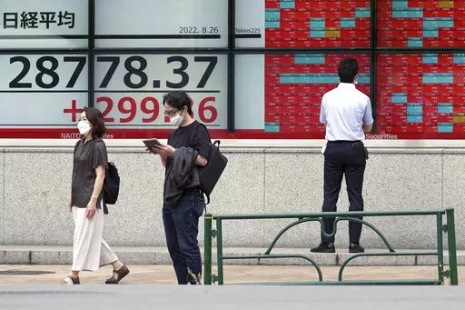 People wearing protective masks stand in front of an electronic stock board showing Japan's Nikkei 225 index at a securities firm Friday, Aug. 26, 2022, in Tokyo. Asian stock markets followed Wall Street higher on Friday ahead of speech by the Federal Reserve chair that investors hoped would shed light on plans for more interest rate hikes. (AP Photo/Eugene Hoshiko)