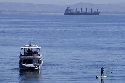 A person paddle boards near a boat in McCovey Cove in San Francisco, Sunday, Sept. 4, 2022. (AP Photo/Jeff Chiu)