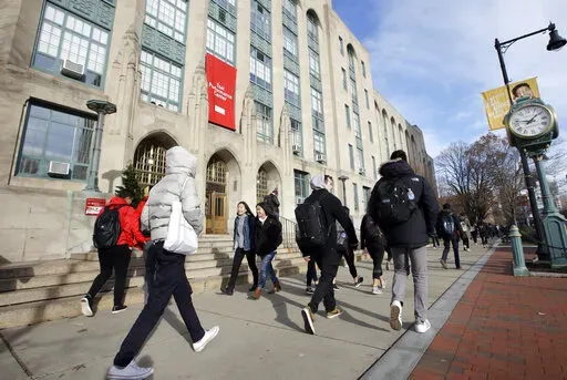 In this Thursday, Nov. 29, 2018, photo students and passers-by walk past an entrance to Boston University College of Arts and Sciences in Boston.  Graduating from college brings with it a lot of change, and that might mean a shift in your financial situation. With just a couple of months before another class leaves college behind, now is the time to start prepping your money to make the transition a little bit easier.  (AP Photo/Steven Senne, File)
