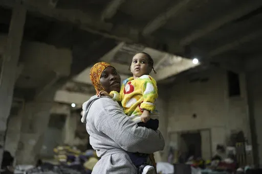 Sierra Leonean migrant worker Isatta Bah, 24, smiles as she holds her daughter, Blessing, one year old, during an interview with The Associated Press while waiting to be repatriated back home, as they are sheltered at a former car dealership in Hazmieh, east of Beirut, Lebanon, Wednesday, Dec. 4, 2024. (AP Photo/Hassan Ammar)