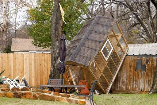 A greenhouse sits on a fence in the backyard of Randy Popiel's home after a possible tornado in Grapevine, Texas, Tuesday, Dec. 13, 2022. (Elías Valverde II/The Dallas Morning News via AP)