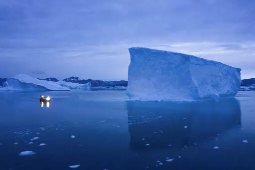 A boat navigates at night next to large icebergs in eastern Greenland on Aug. 15, 2019. Zombie ice from the massive Greenland ice sheet will eventually raise global sea level by at least 10 inches (27 centimeters) on its own, according to a study released Monday, Aug. 29, 2022.  Zombie or doomed ice is still attached to thicker areas of ice, but it’s no longer getting fed by those larger glaciers.  (AP Photo/Felipe Dana, File)